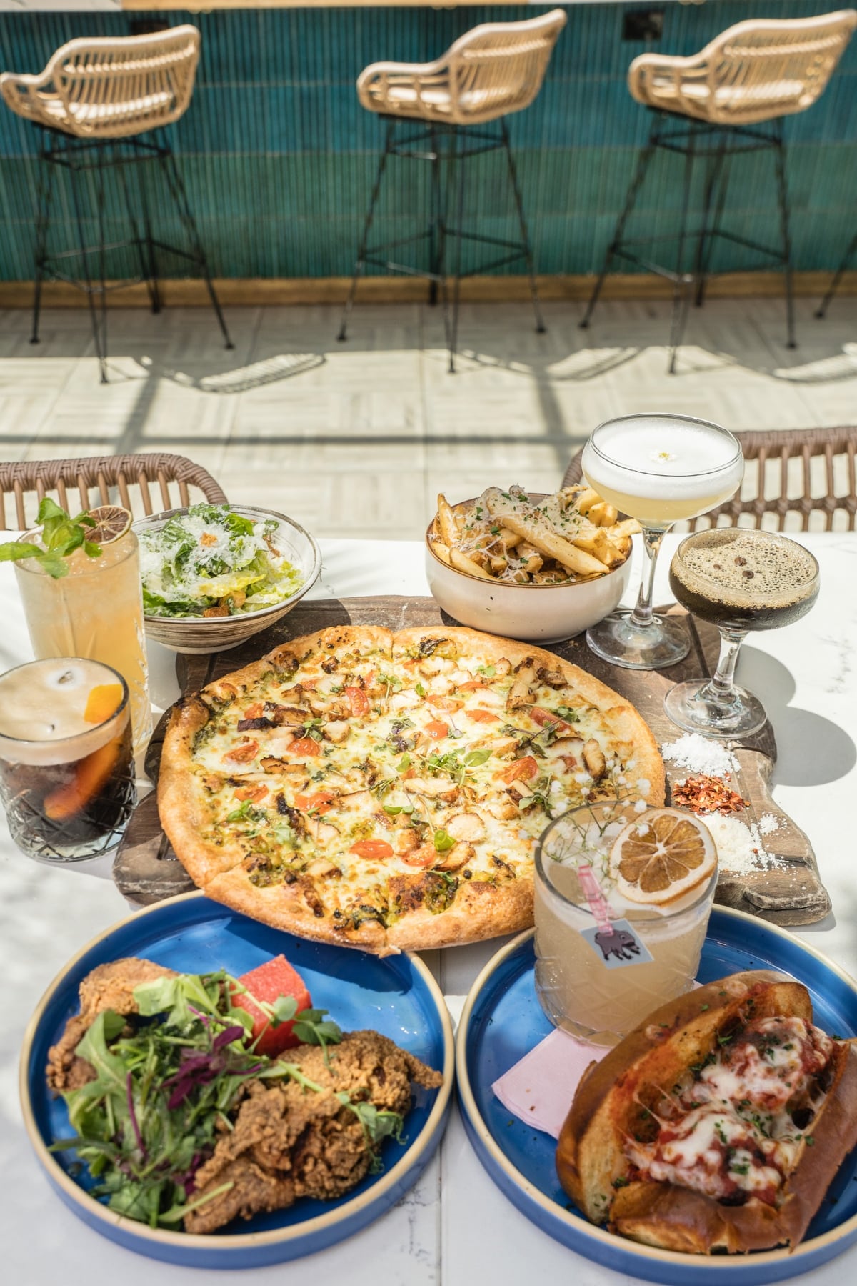Happy hour spread with pizza, meatball sub, fried chicken, fries, caesar salad and cocktails at Coco Maya