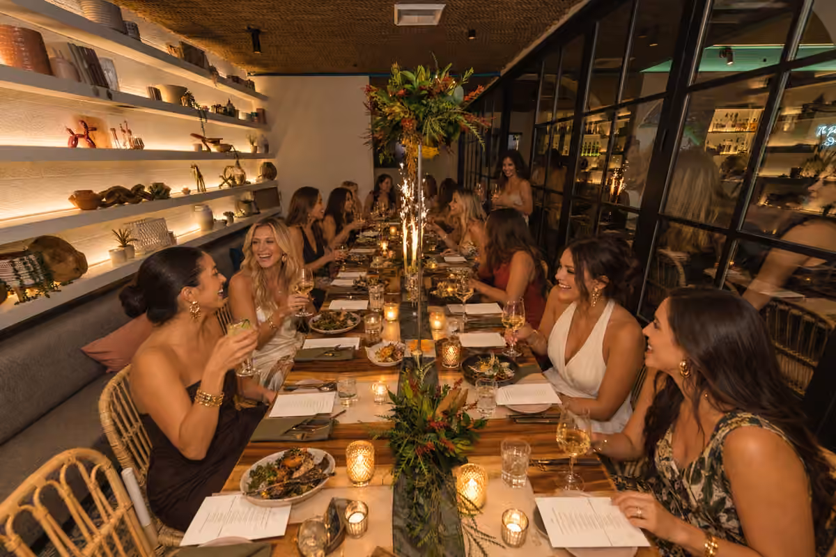 Company holiday party guests dining around a decorated table at Coco Maya in Little Italy San Diego